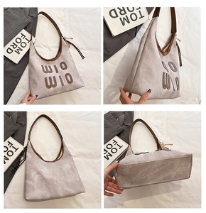 Detail view of large grey tote bag with WIO WIO embroidery and woven pendant charm