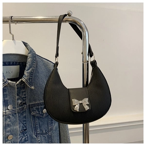 Detail of silver bow buckle on black moon-shaped shoulder bag with vertical texture