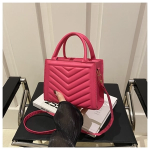 Detail of pink quilted leather bag with V-shaped stitching and gold-tone hardware detail
