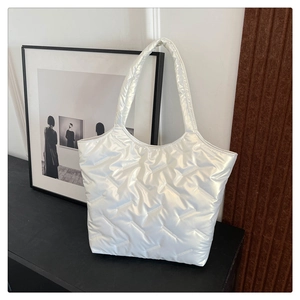 Vue détaillée du sac cabas matelassé blanc à finition brillante sur fond sombre