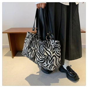 Detail der Zebra-Canvas-Tasche mit goldenen Metallringen und schwarzen Lederriemen