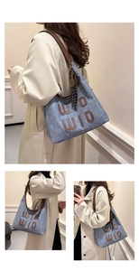 Detail of blue denim tote bag with brown leather straps and WIO WIO letter embroidery