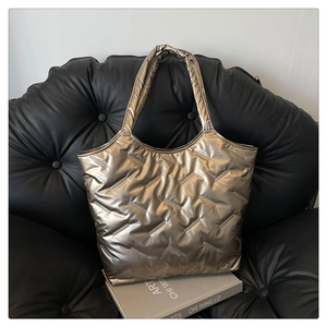 Détails de la texture du sac cabas matelassé bronze sur un canapé en cuir