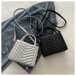 Detailed view of silver and black V-quilted handbags with gold hardware on denim