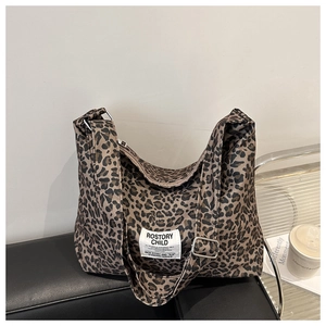 Détail du sac cabas léopard avec bandoulière ajustable posé sur un canapé noir