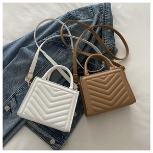 Detailed view of white and brown quilted handbags with gold hardware on denim background
