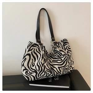 Detailansicht der Zebra-Tragetasche mit goldenen Metallringen und schwarzem Lederriemen