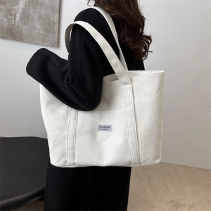 Minimalist white corduroy tote bag with Fashion Instinct label worn by model