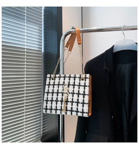 Detail of checkered tote bag with gold S-buckle, leather trim and elegant metal chain