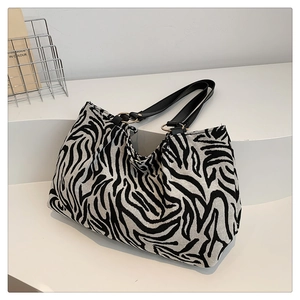Detail der Zebra-Canvas-Tasche mit goldenen Metallringen und schwarzen Lederriemen
