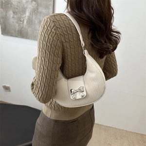 Chic cream white pleated crescent shoulder bag with silver bow detail worn by model