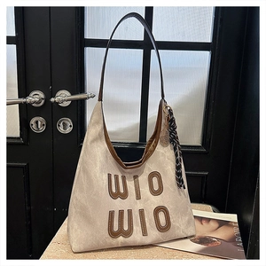 Close-up of beige canvas tote bag with brown WIO WIO lettering and leather piping detail