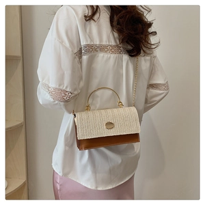 Detailed view of woven straw and leather crossbody bag with a gold metal ring handle