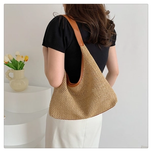 Close-up of a woven straw tote bag with brown leather handles on a minimal background