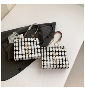 Detail of tweed checkered tote bags with gold metal logo and leather chain straps