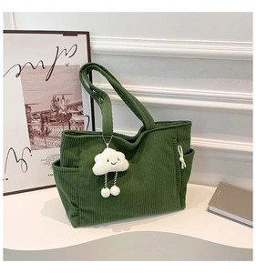 Detailed view of dark green corduroy tote bag featuring a cute white cloud plush pendant