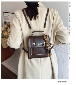 Detail of vintage brown PU leather backpack with wavy edge and cute rabbit doll charm