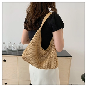 Detail view of woven khaki straw tote bag on a model showing the texture and strap