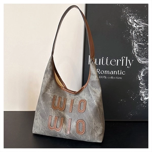 Detail of grey canvas tote bag with leather straps and vertical WIO letter patches