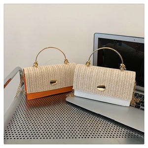 Detail of woven straw flap and gold ring handle on a stylish patchwork crossbody bag