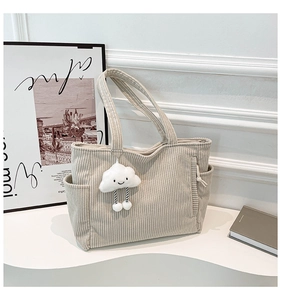 Detail of beige corduroy tote bag showing ribbed texture and cute cloud charm accessory