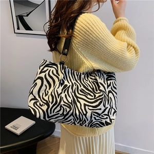 Zebra-Canvas-Tasche mit schwarzen Lederriemen und Goldringen an einem Modell