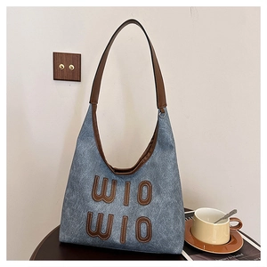 Detail shot of the blue denim tote bag featuring brown leather WIO WIO letter embroidery