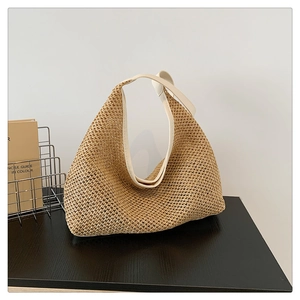 Close-up of bohemian woven tote bag with straw texture and white trim on a wooden table