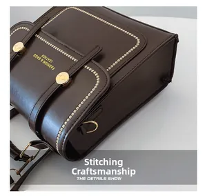 Detail of dark brown leather crossbody bag with white stitching and gold hardware