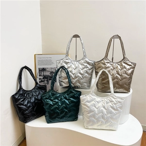 Cinq sacs cabas matelassés de couleurs variées présentés sur des supports de studio