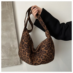 Gros plan d'un sac demi-lune imprimé léopard en daim marron avec large bandoulière