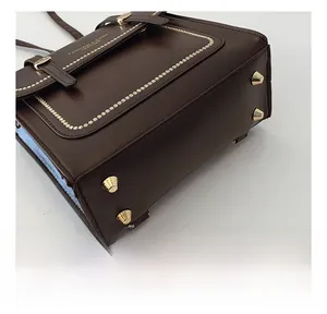 Close-up of dark brown leather bag base with gold metal feet and beaded stitching detail