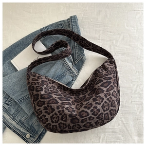 Sac croissant à imprimé léopard présenté avec une veste en jean sur tissu blanc