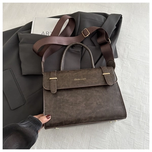Détail du sac vintage en cuir marron avec boucle dorée et lettrage mode chic