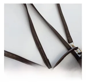 Detail of dark brown leather shoulder straps with reinforced stitching and gold metal rings