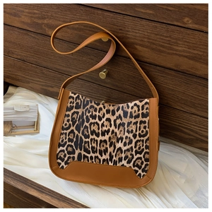 Gros plan du sac à bandoulière léopard avec bordure en cuir marron caramel et décor en bois