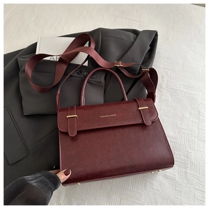 Détail du sac bandoulière en cuir bordeaux avec finitions dorées et large bandoulière