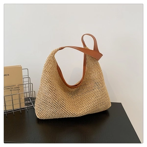 Detail of hand-woven straw tote with premium brown leather handles in bohemian style