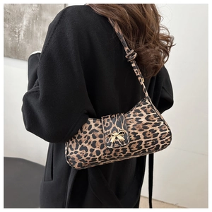 Detail of leopard print shoulder bag with gold bow clasp and knotted strap detail