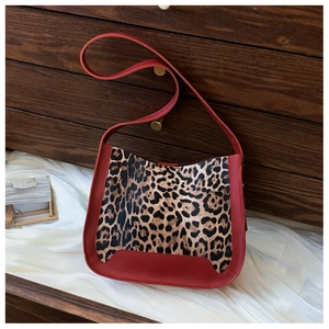Détail de la texture léopard et des finitions en cuir rouge sur le grand sac à main