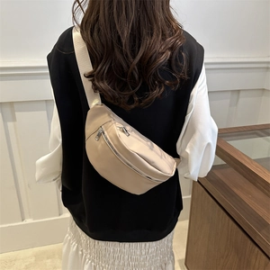 Minimalist beige crossbody chest bag with adjustable strap shown on model from behind