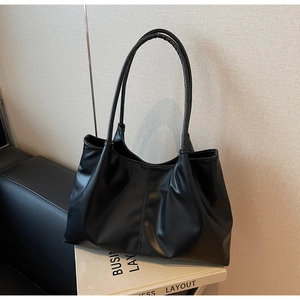 Detail of minimalist black tote bag with vertical stitching and textured pleats