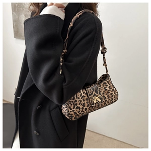 Detail of leopard print shoulder bag featuring a golden bow buckle on a wool coat