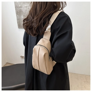 Detailed view of beige pleated crossbody chest bag with adjustable strap on model
