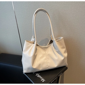 Detail view of large cream leather tote bag featuring center seam and pleated texture