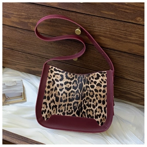 Détail du cuir bordeaux et du tissu peluche léopard sur un sac demi-lune oversize