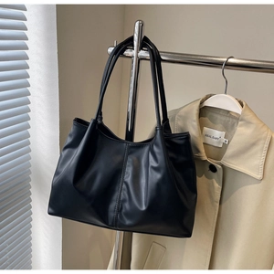 Detail view of black PU leather tote bag with soft pleated texture and vertical stitching