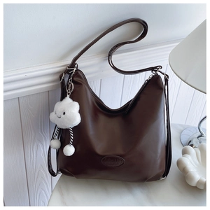 Detail of dark brown faux leather hobo bag with cloud charm on marble table
