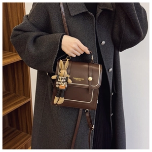 Close-up of brown leather backpack with bead trim and a cute rabbit doll charm