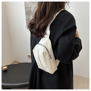 Rear view of white PU leather crossbody bag worn on a black coat showing wide strap